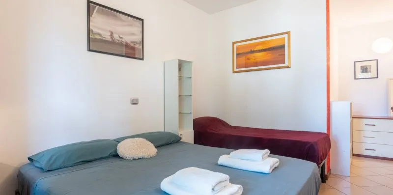 A bedroom with two beds, framed pictures, and a small chest of drawers.