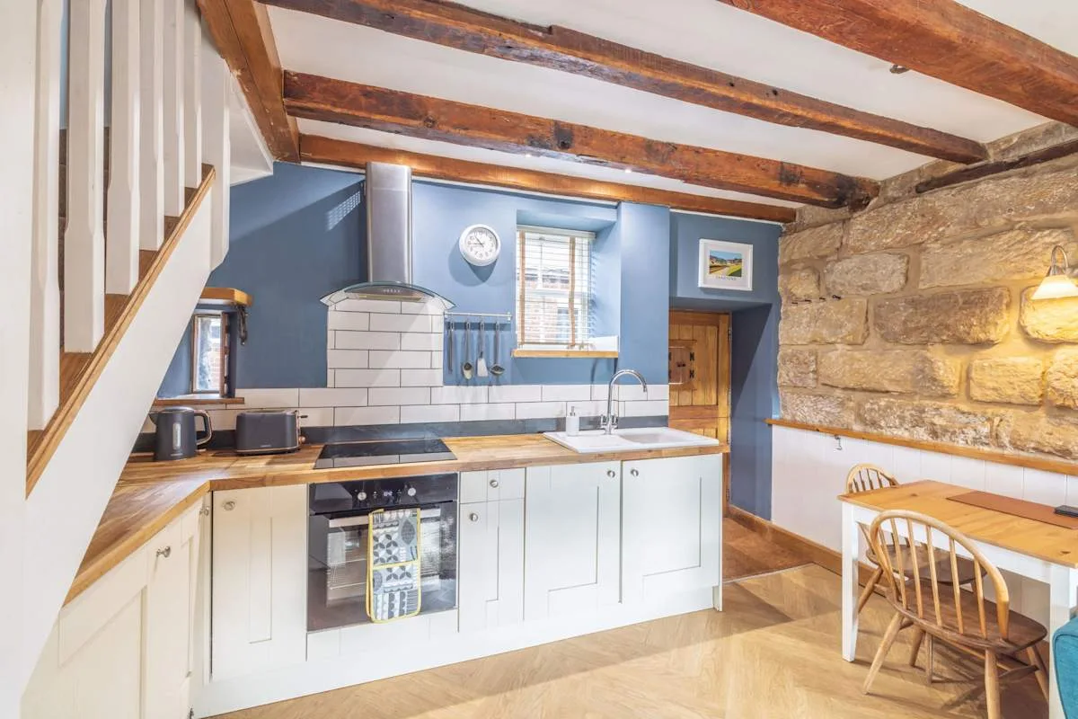 Una cocina con armarios blancos, una cocina y una mesa de comedor de madera.