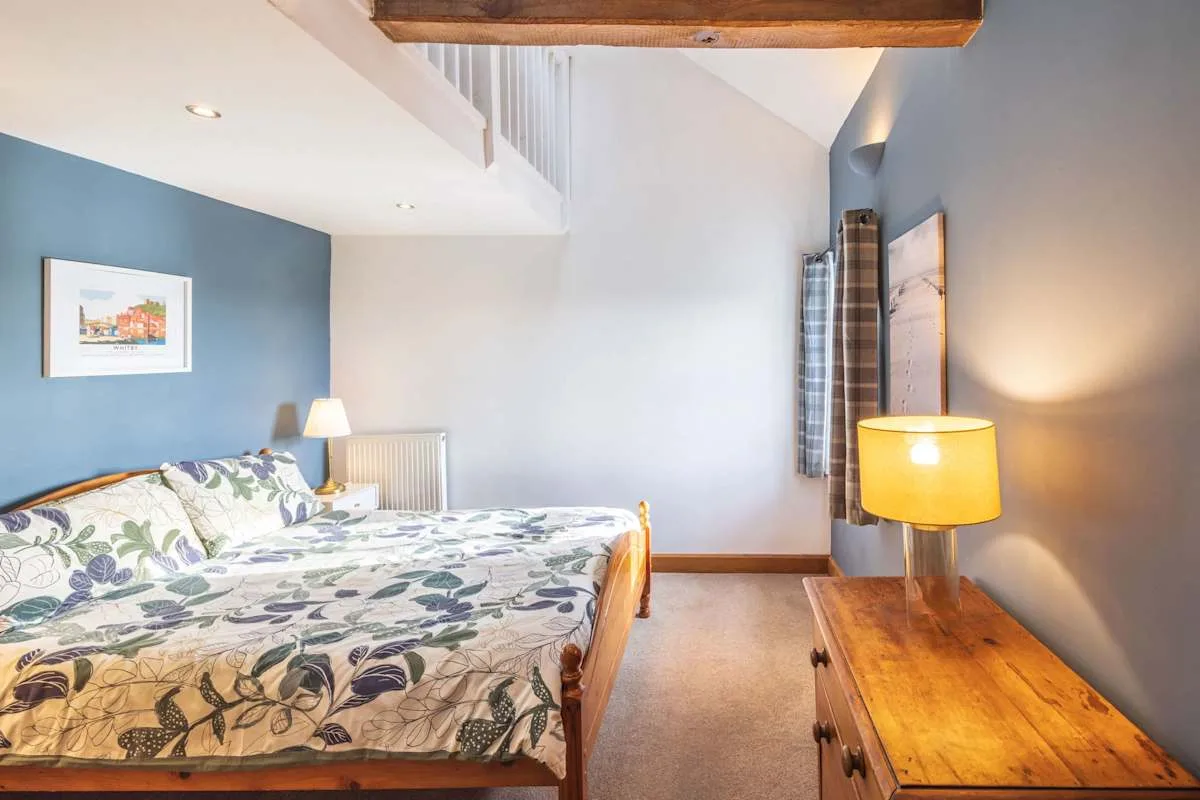 Dormitorio con una colcha estampada y una cómoda de madera.