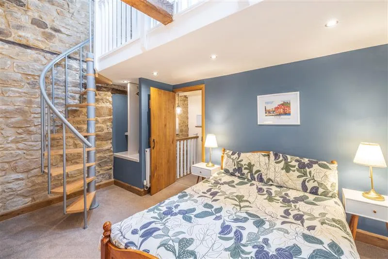 Bedroom with a floral-patterned bed beside a spiral staircase.