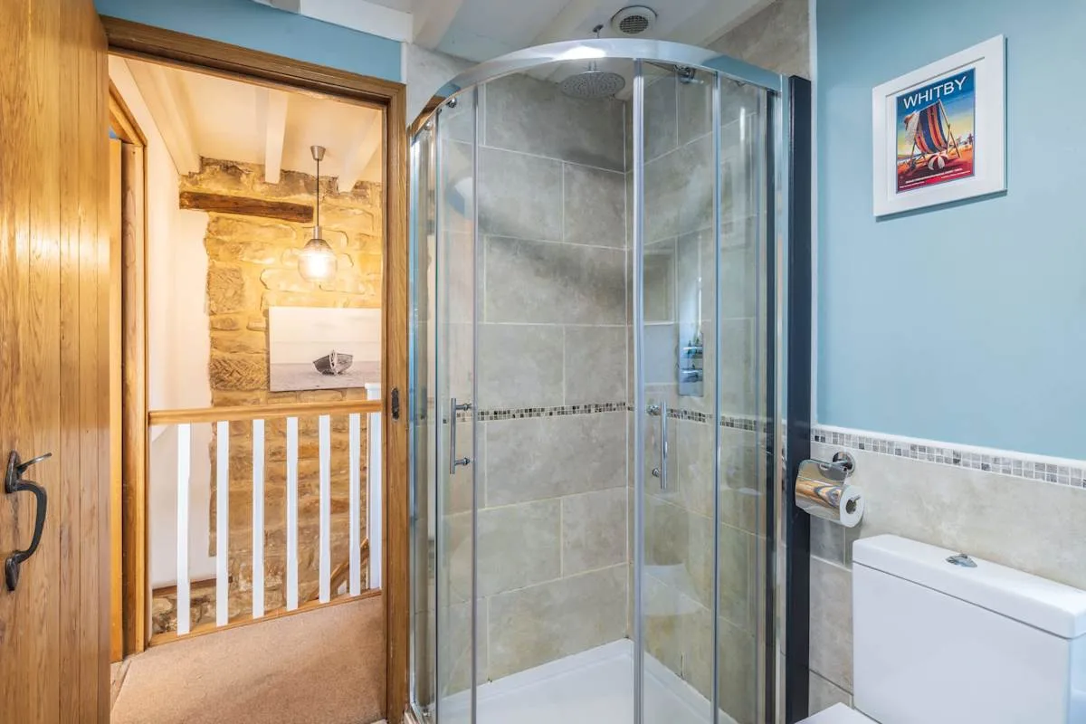 Un baño con una ducha curva de vidrio y un inodoro.