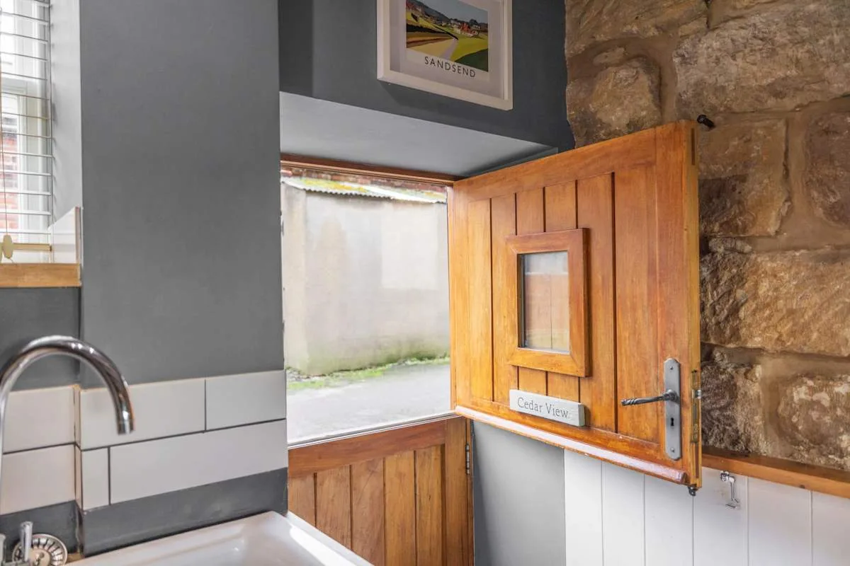 Un fregadero de cocina está junto a una puerta de madera abierta y una pared de piedra.