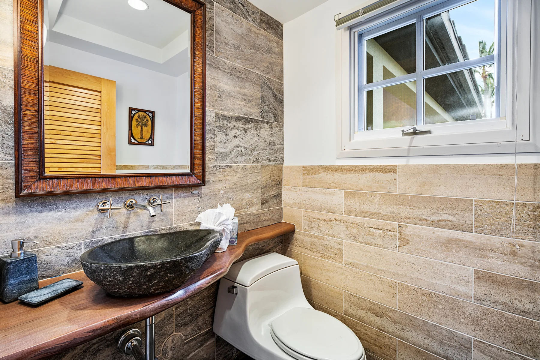 A bathroom with a vessel sink, toilet, and a window.