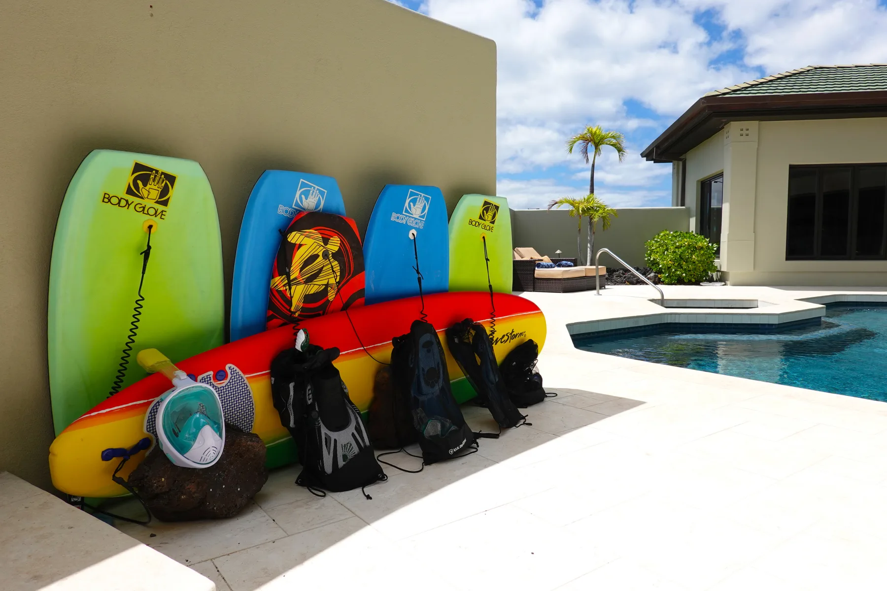 Poolside area with colorful water sports equipment arranged beside the swimming pool.