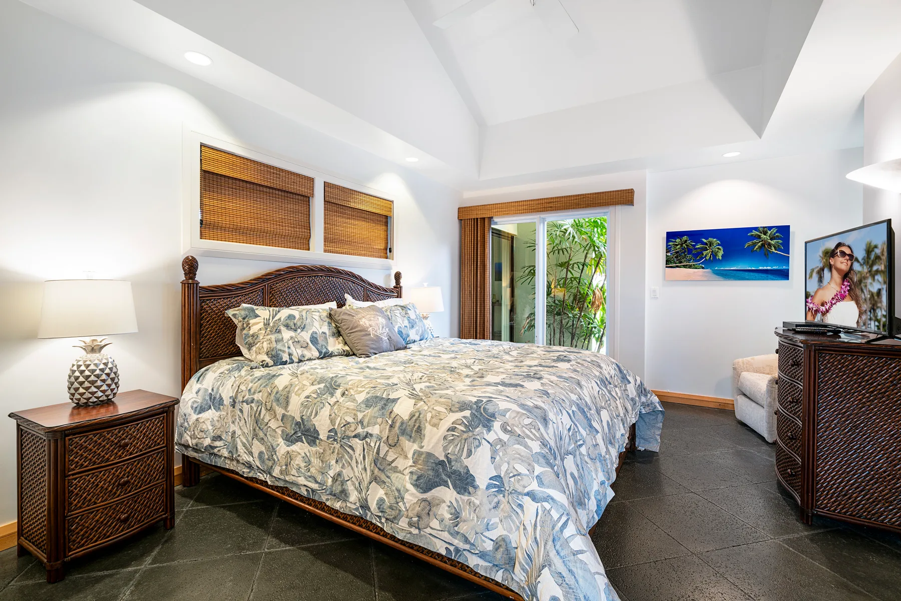 A bedroom with a patterned bedspread and glass doors opening onto greenery.