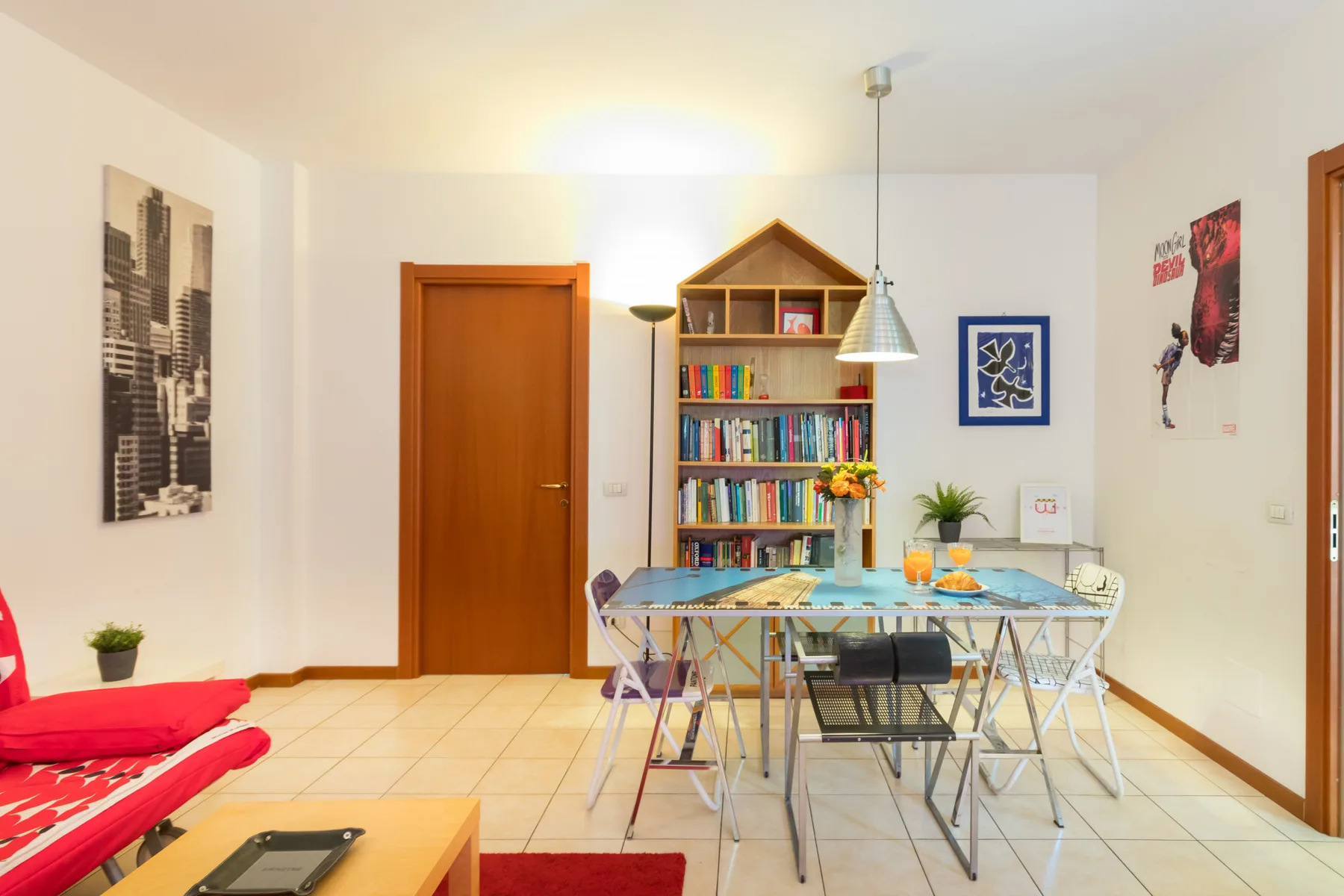 Un comedor con una mesa de cristal y una estantería junto a la pared.