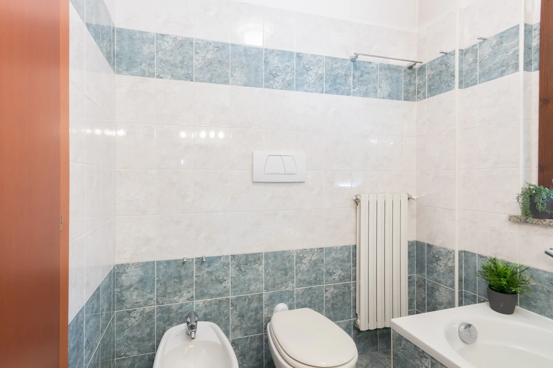Un baño alicatado con inodoro, bidé, radiador y bañera.