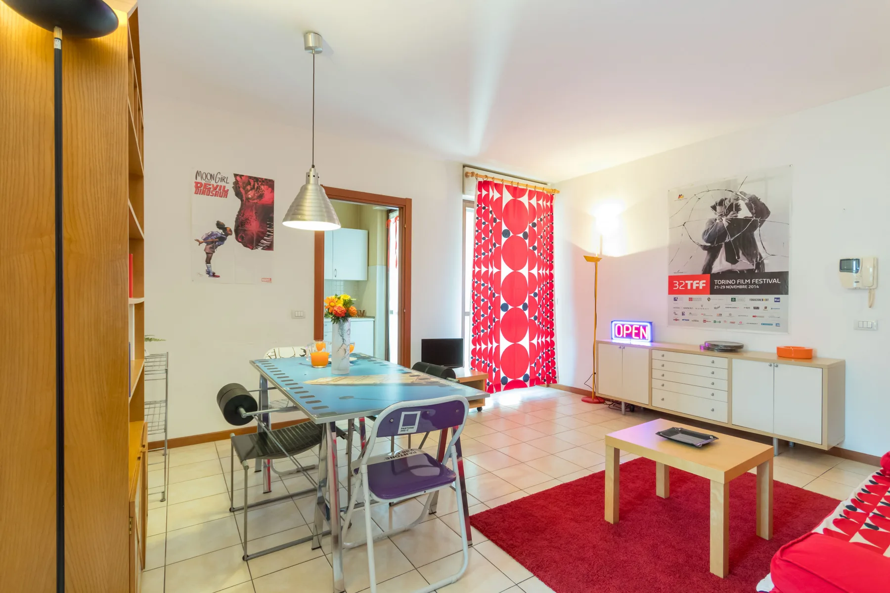 Una luminosa sala-comedor con una mesa, asientos y una alfombra roja.