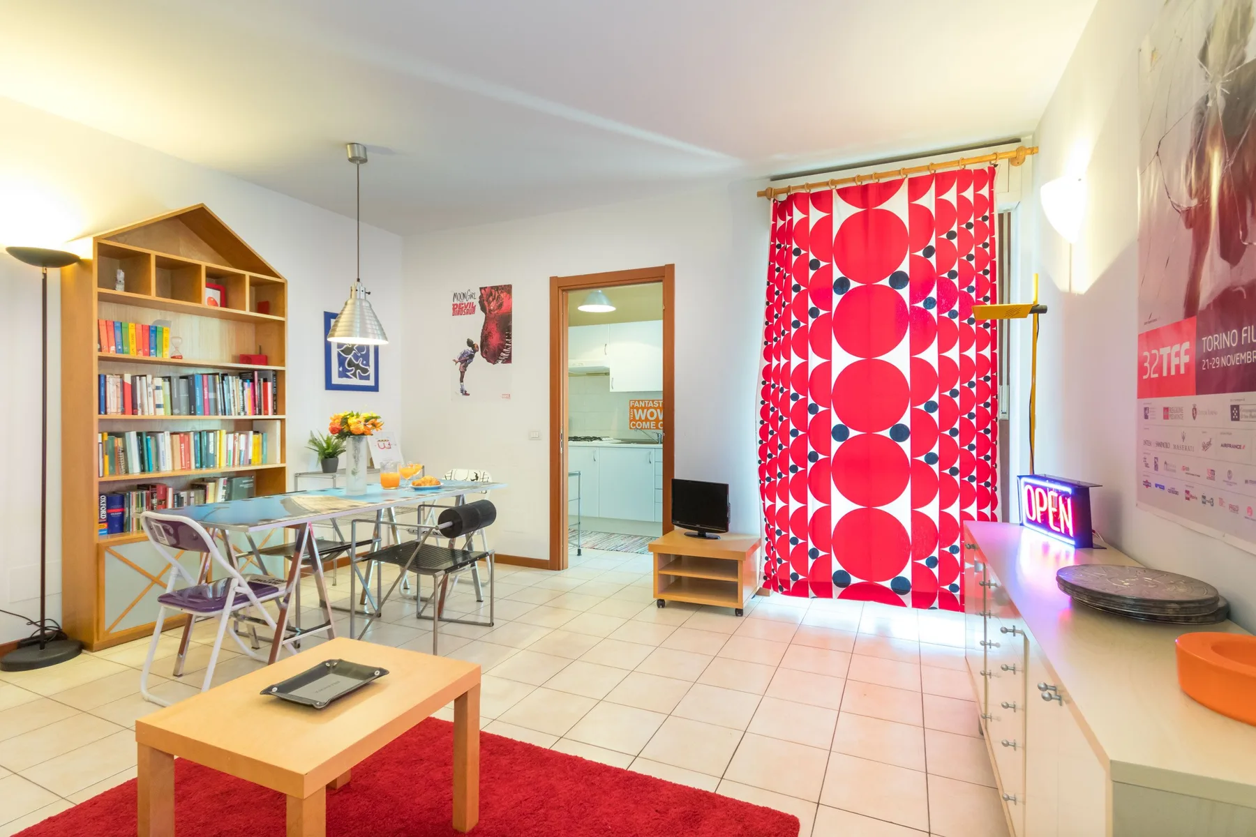 Una luminosa sala de estar y comedor con una mesa de vidrio y cortinas coloridas.