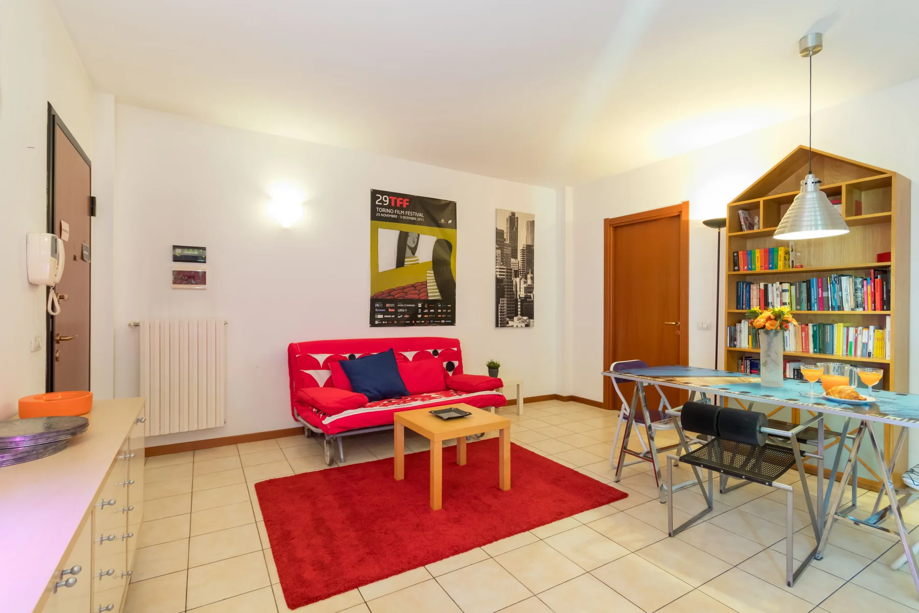 Una sala luminosa con asientos rojos, una mesa de centro y un comedor.