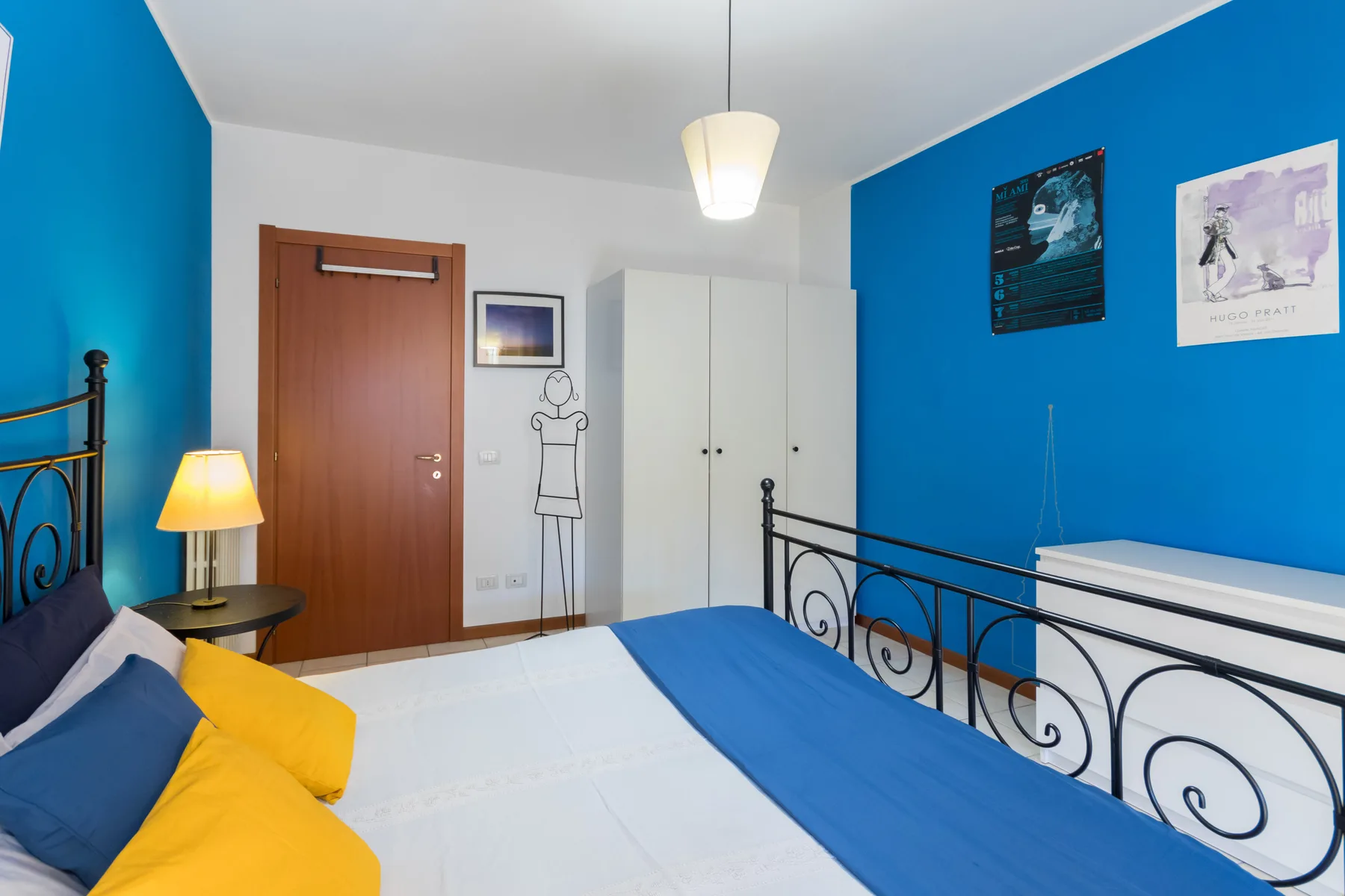 Un dormitorio con una cama, paredes azules y un armario blanco.
