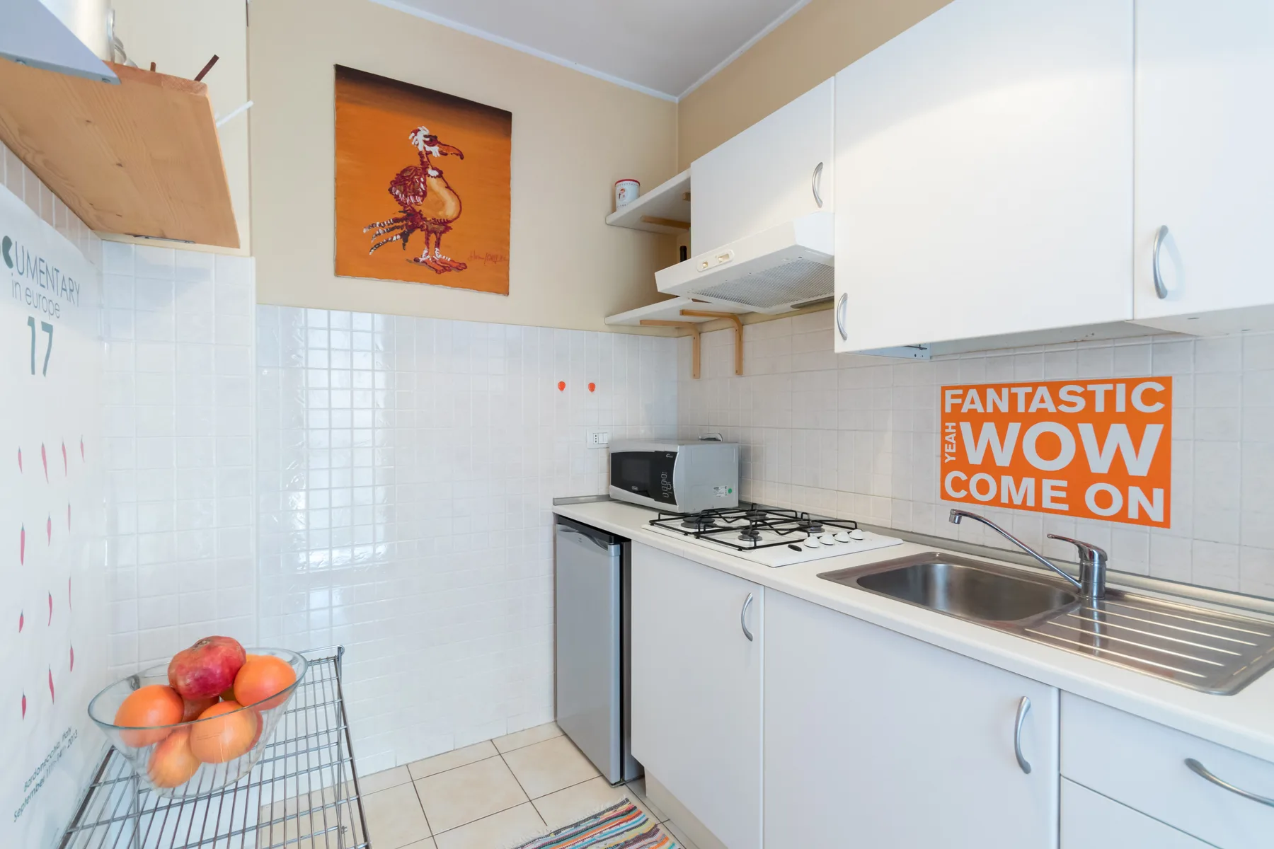 Una cocina compacta con armarios blancos, una encimera y un fregadero.