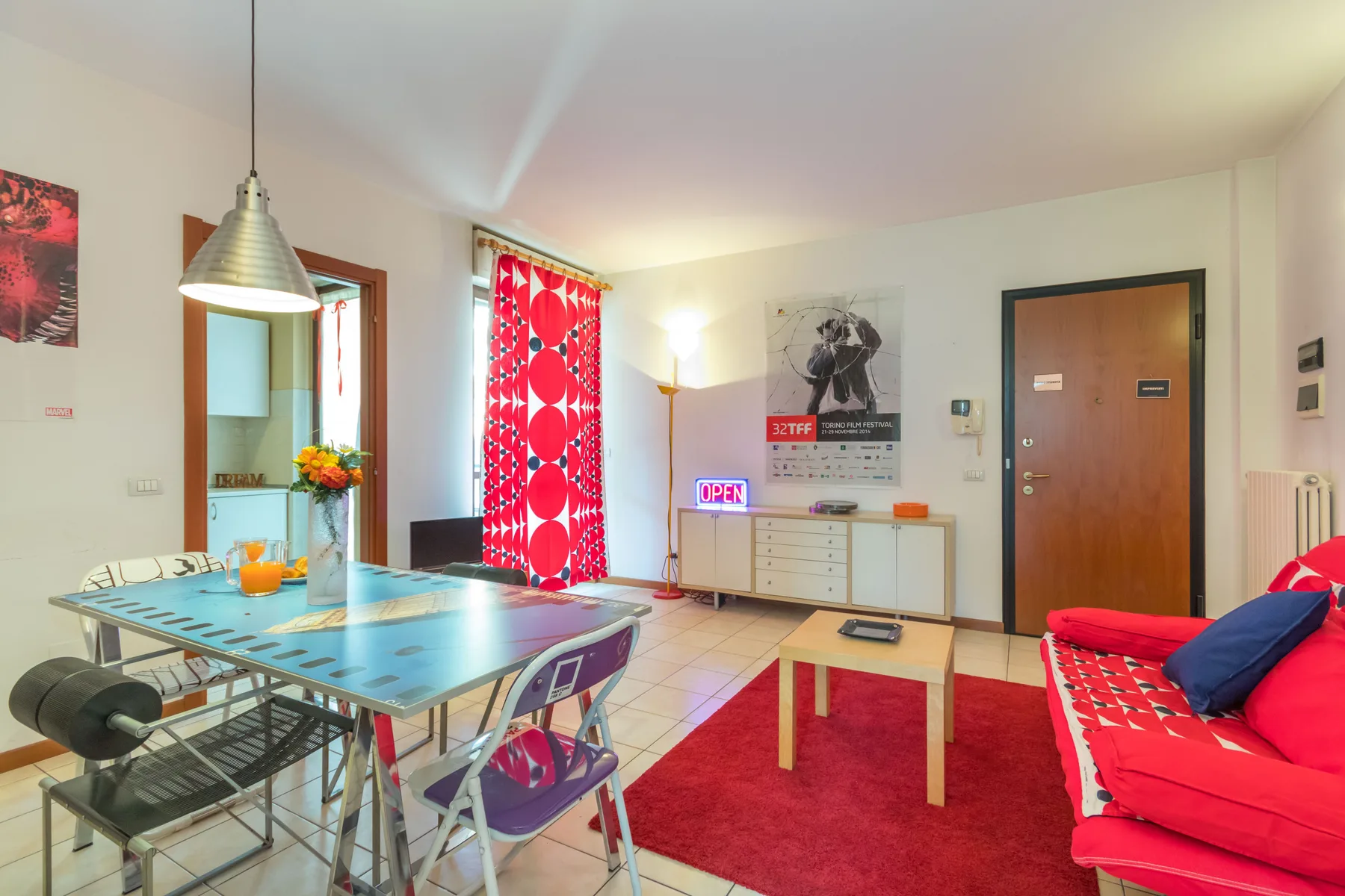 Una sala colorida con mesa de comedor, alfombra roja y asientos llamativos.