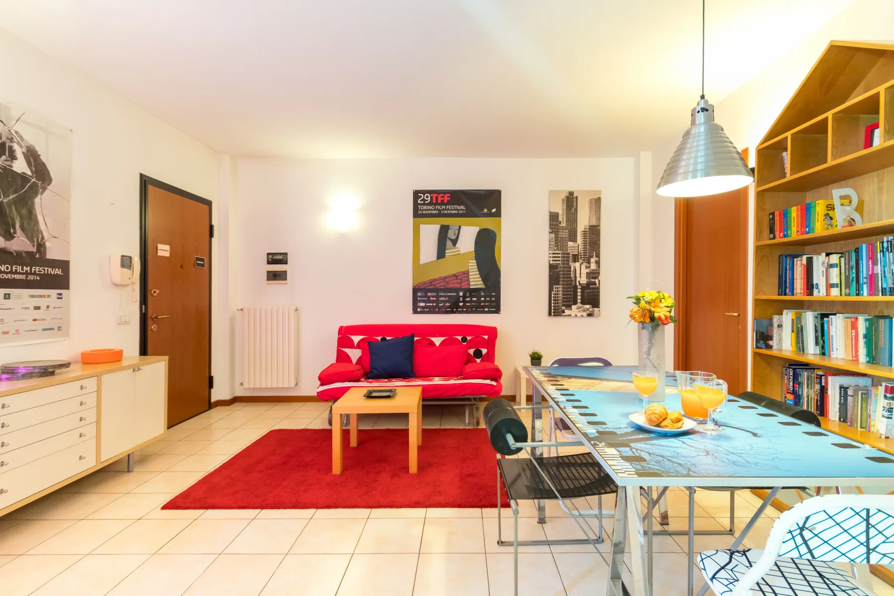 Una sala de estar luminosa con asientos rojos, una mesa baja y un comedor.