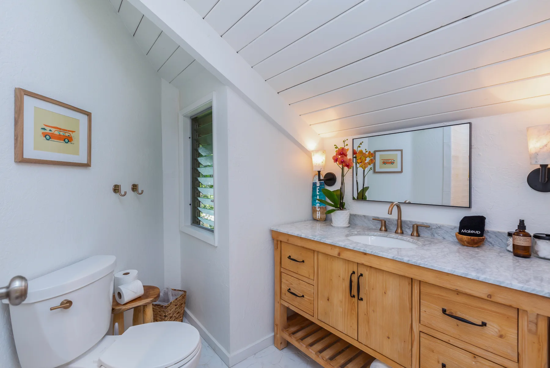 A bright bathroom with a long vanity, large mirror, and toilet.
