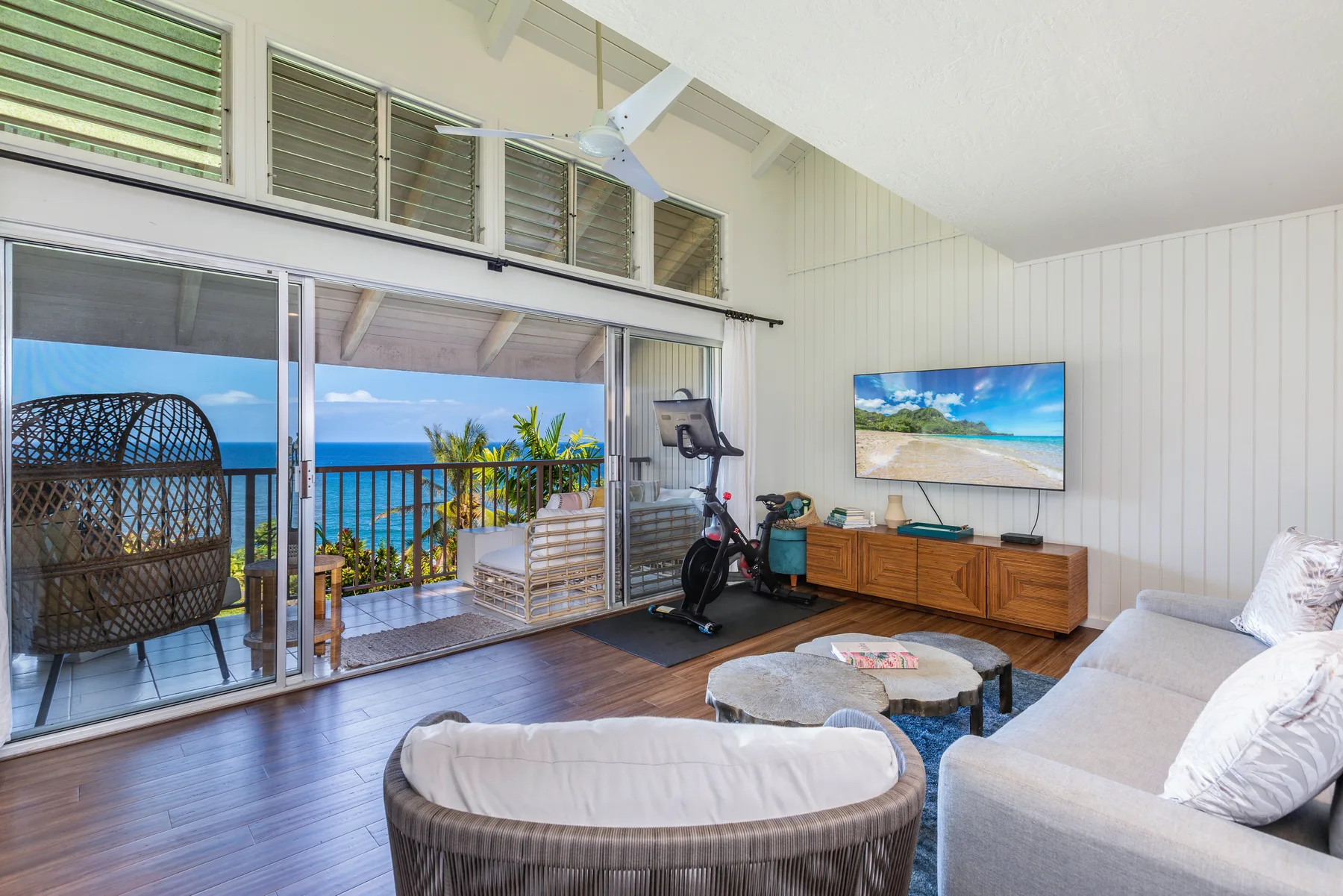 A bright living room opens onto a balcony with ocean views.