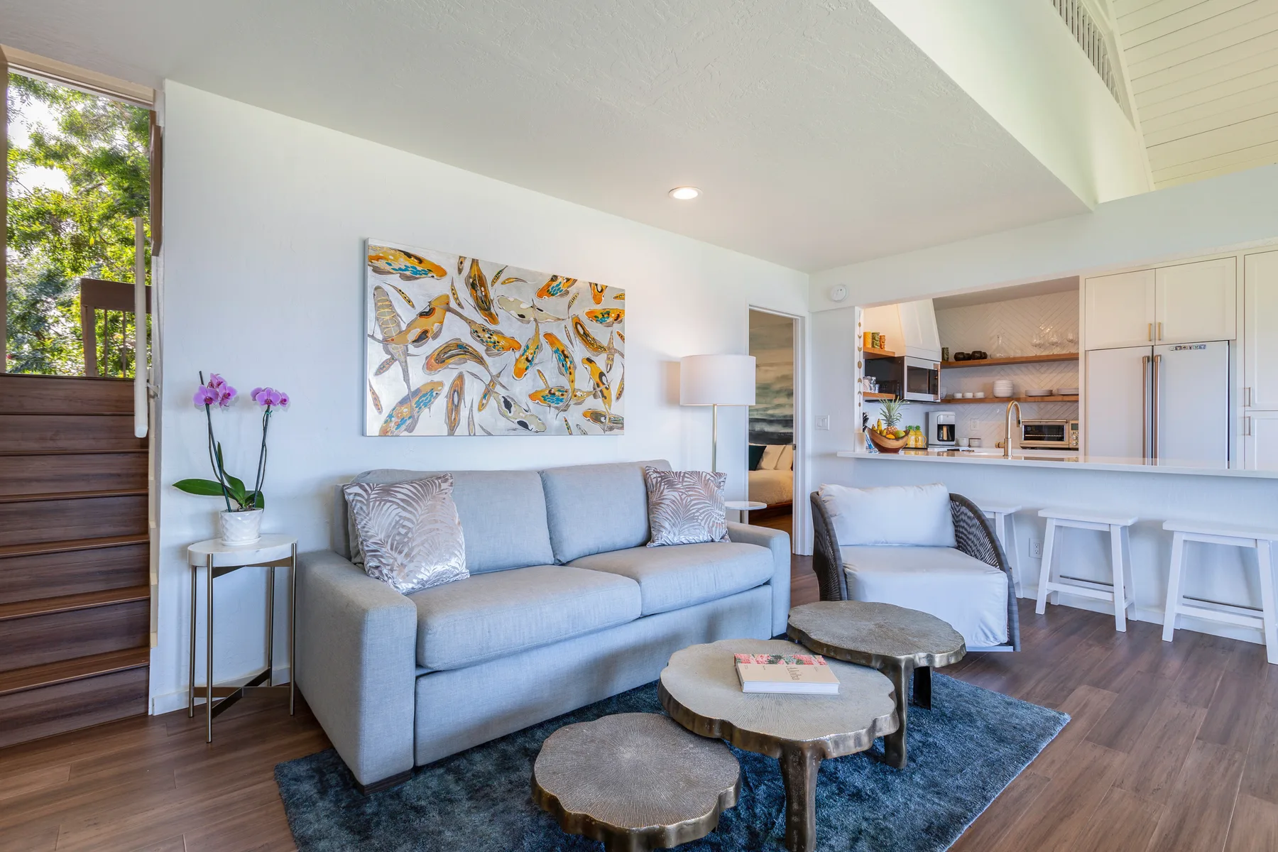 A living room with a sofa, coffee tables, and an open kitchen.