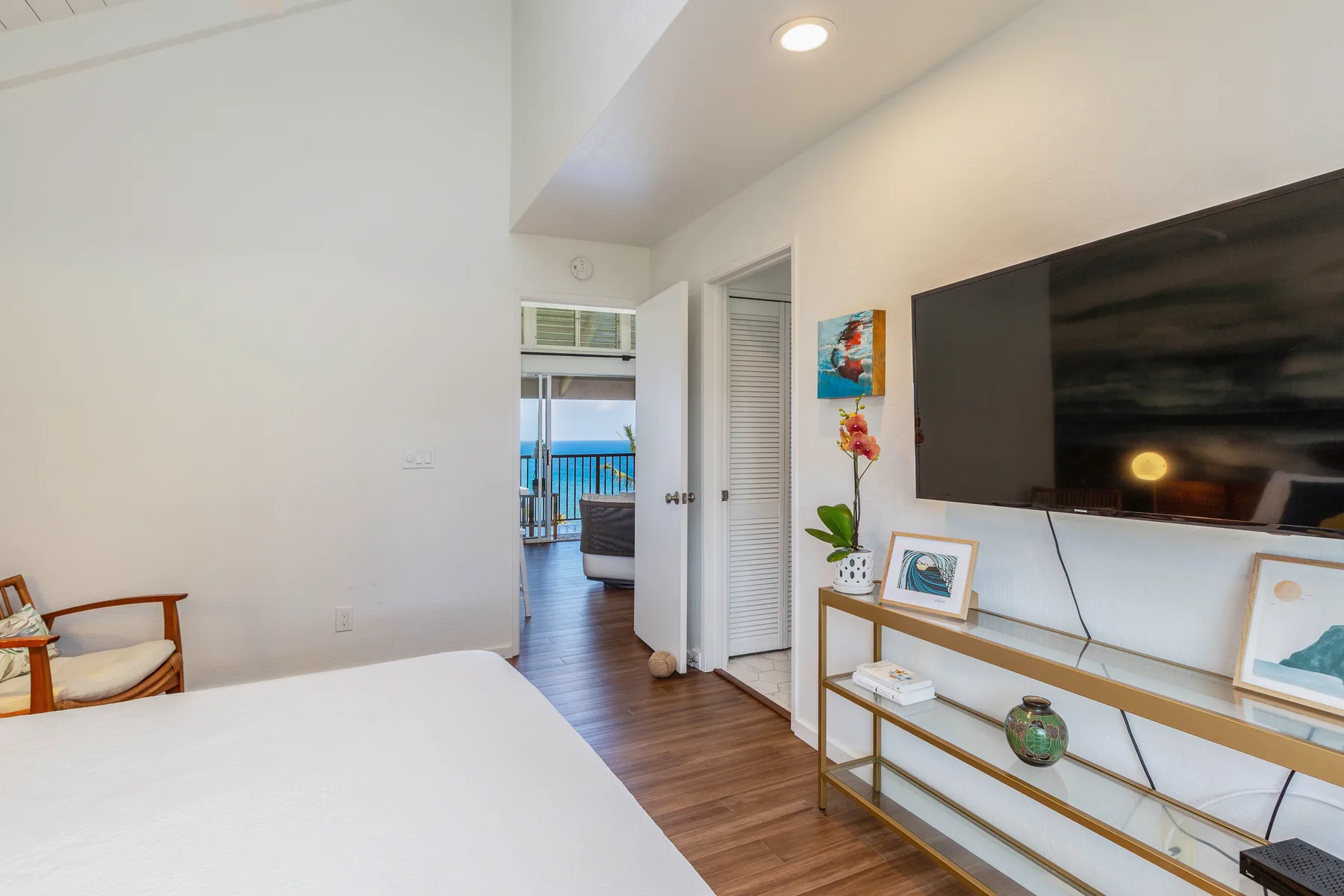A bright bedroom with a bed, television, and an open doorway to a balcony.