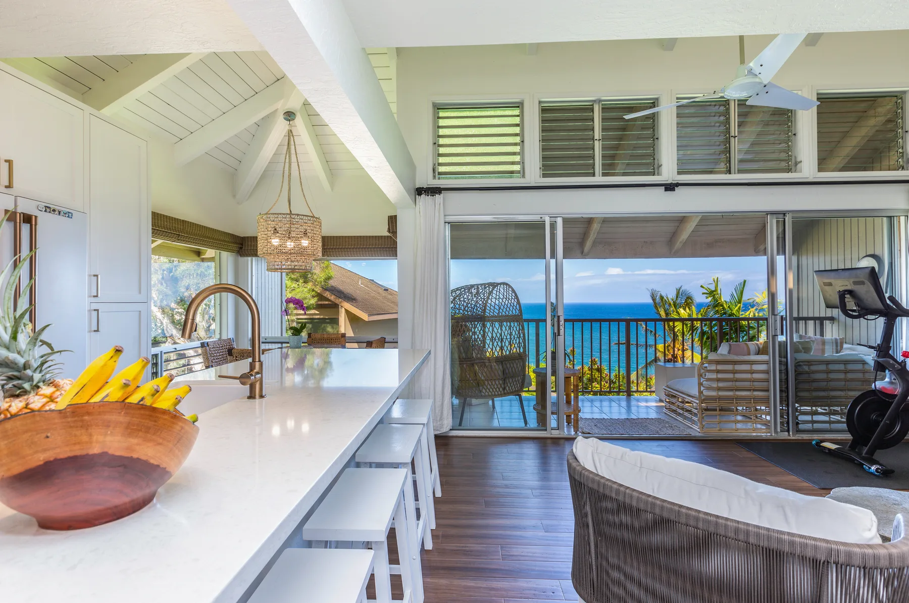 An open kitchen and living area opens onto a balcony with an ocean view.