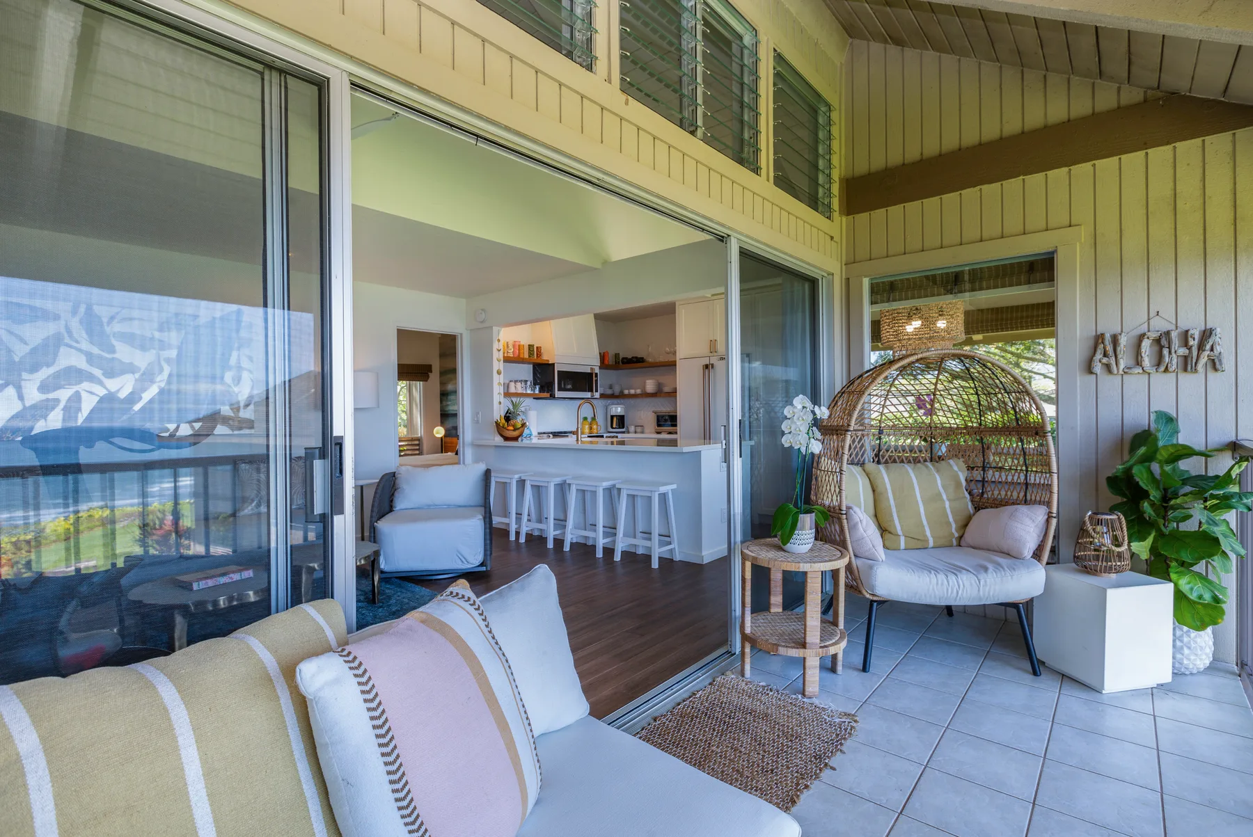 A bright patio seating area opens onto a kitchen through wide sliding glass doors.