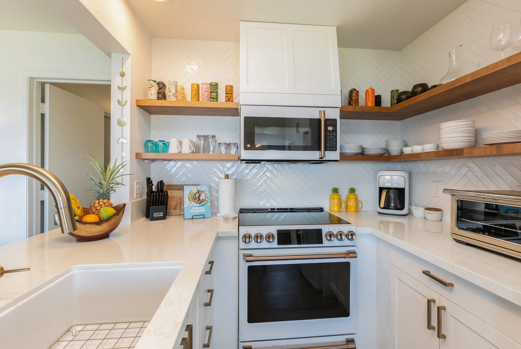 A bright kitchen with white cabinets, open shelves, and a stainless steel range.
