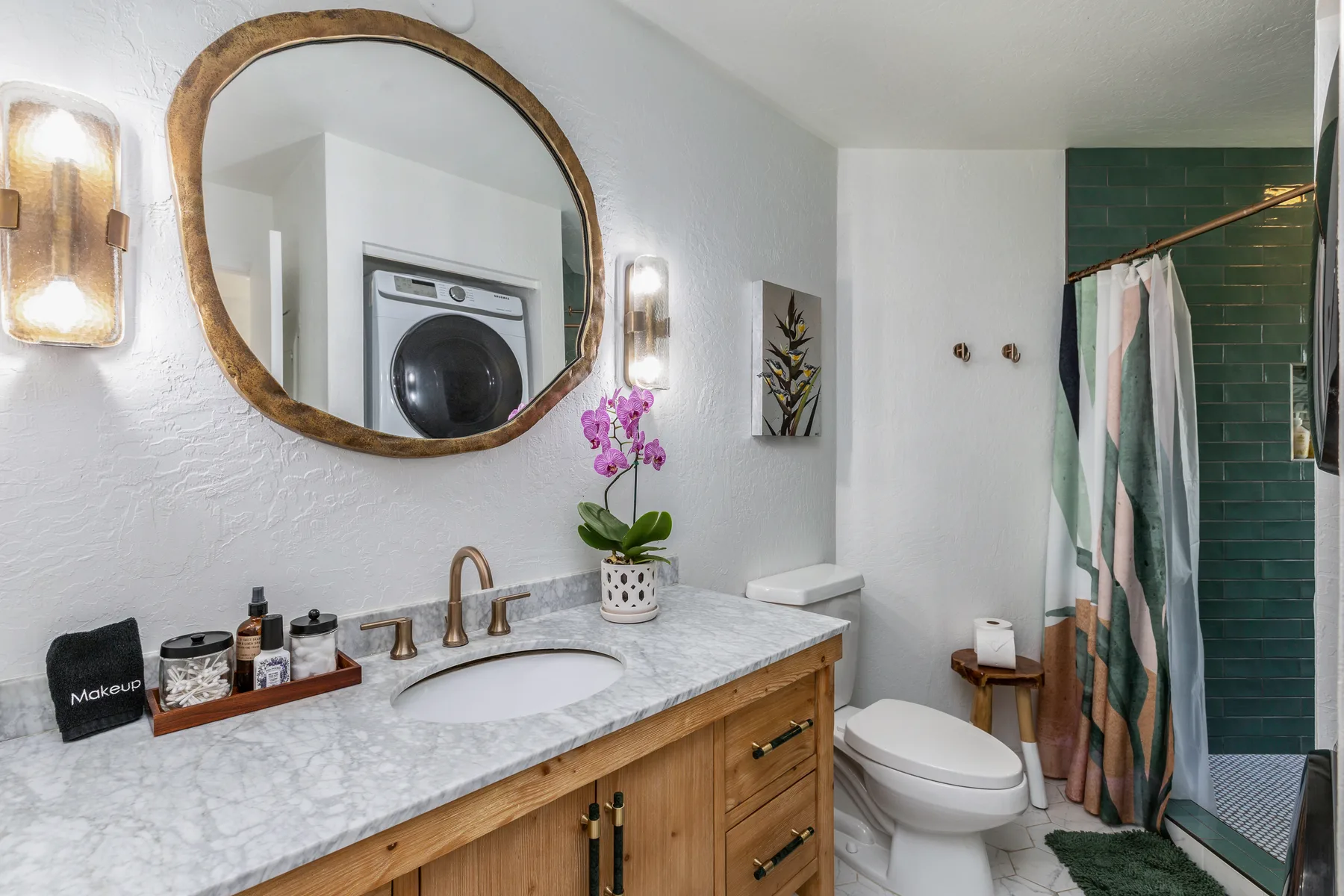 A bathroom vanity with a sink, mirror, and toilet beside a tiled shower.