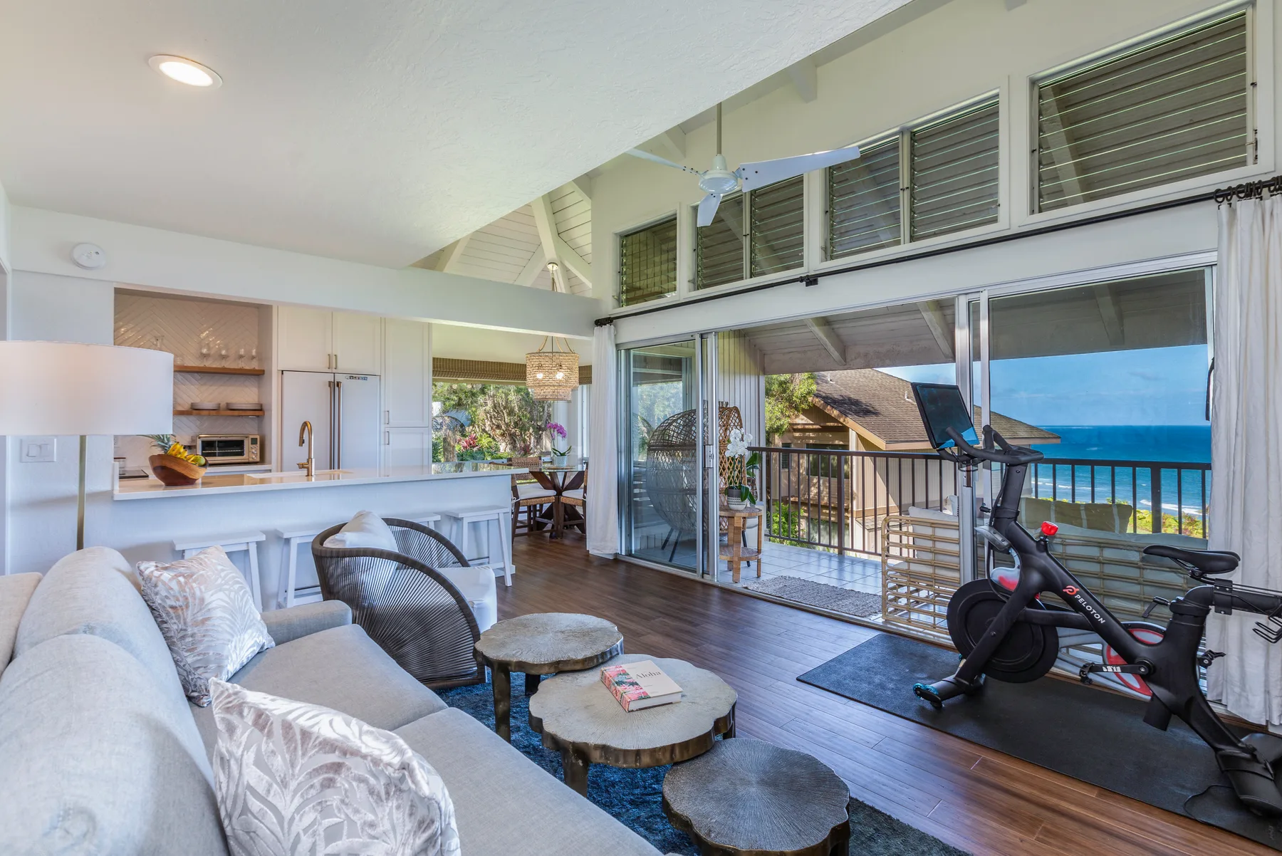 A bright living room opens onto a balcony with ocean views.