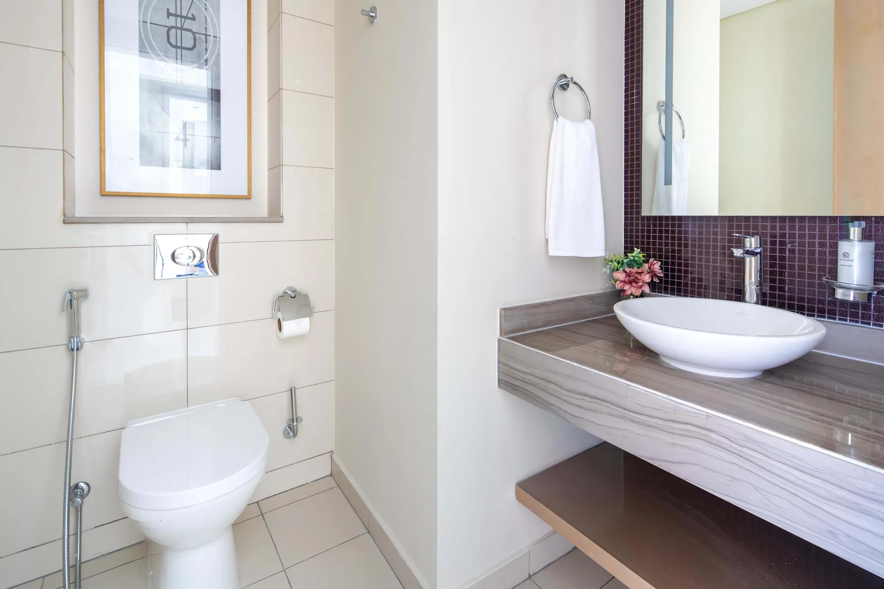Un baño moderno con un inodoro suspendido y un lavabo sobre una encimera.