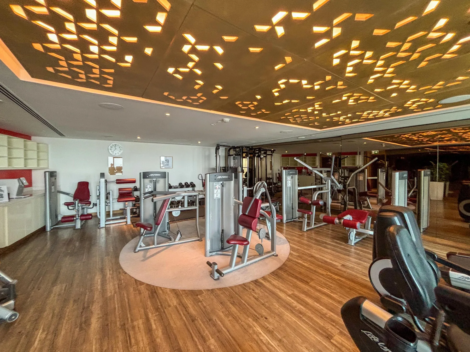 Un gimnasio con máquinas de ejercicio distribuidas sobre un suelo de madera.