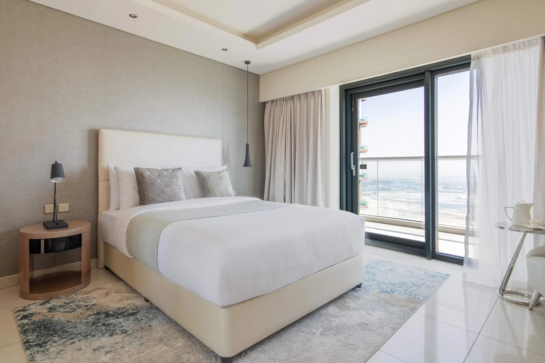 Un dormitorio con una cama junto a grandes ventanales con vistas al mar.