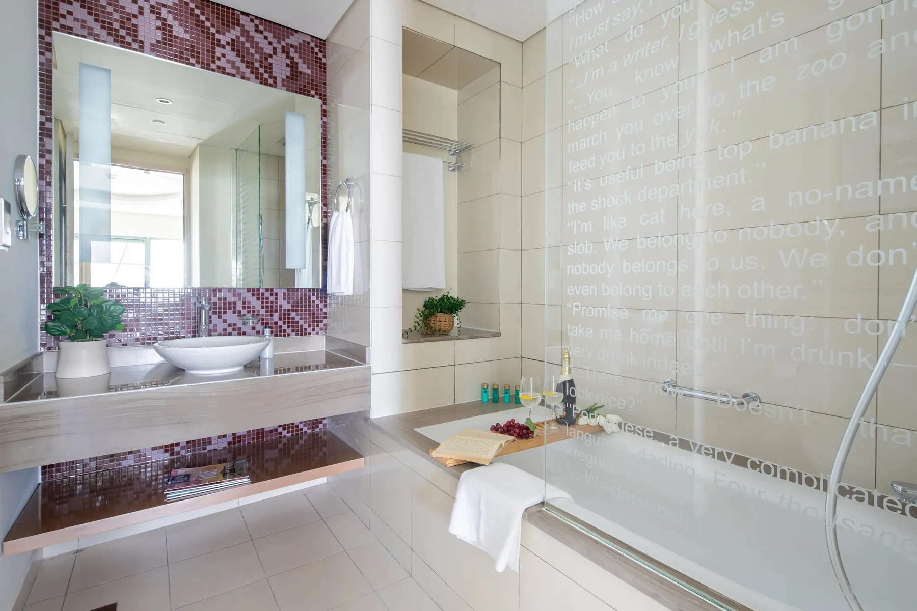 Un baño luminoso con azulejos, bañera, mampara de vidrio y lavabo.