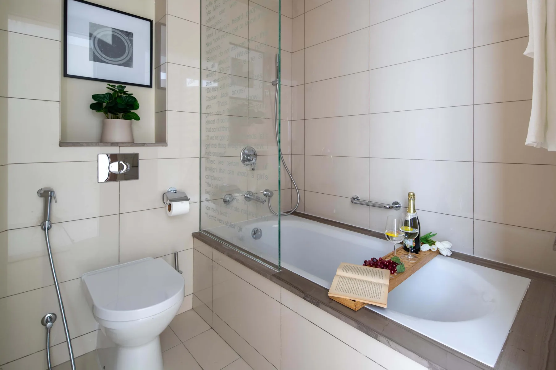Un baño alicatado con bañera, mampara de vidrio y retrete.