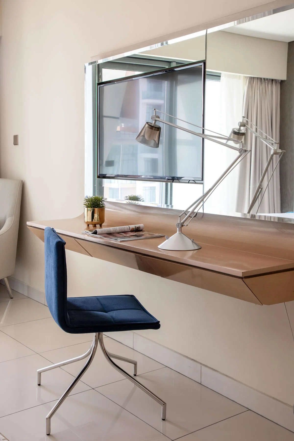 Un escritorio y una silla están junto a una ventana grande en una habitación luminosa.