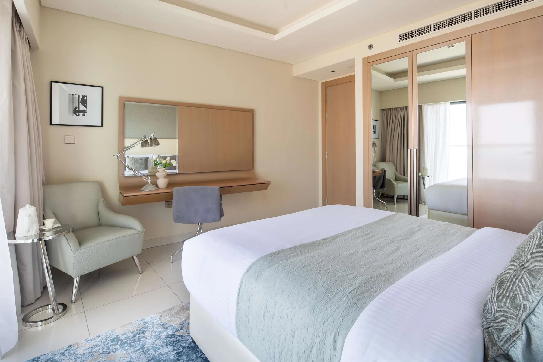 Un dormitorio con una cama, un escritorio y un asiento acolchado.