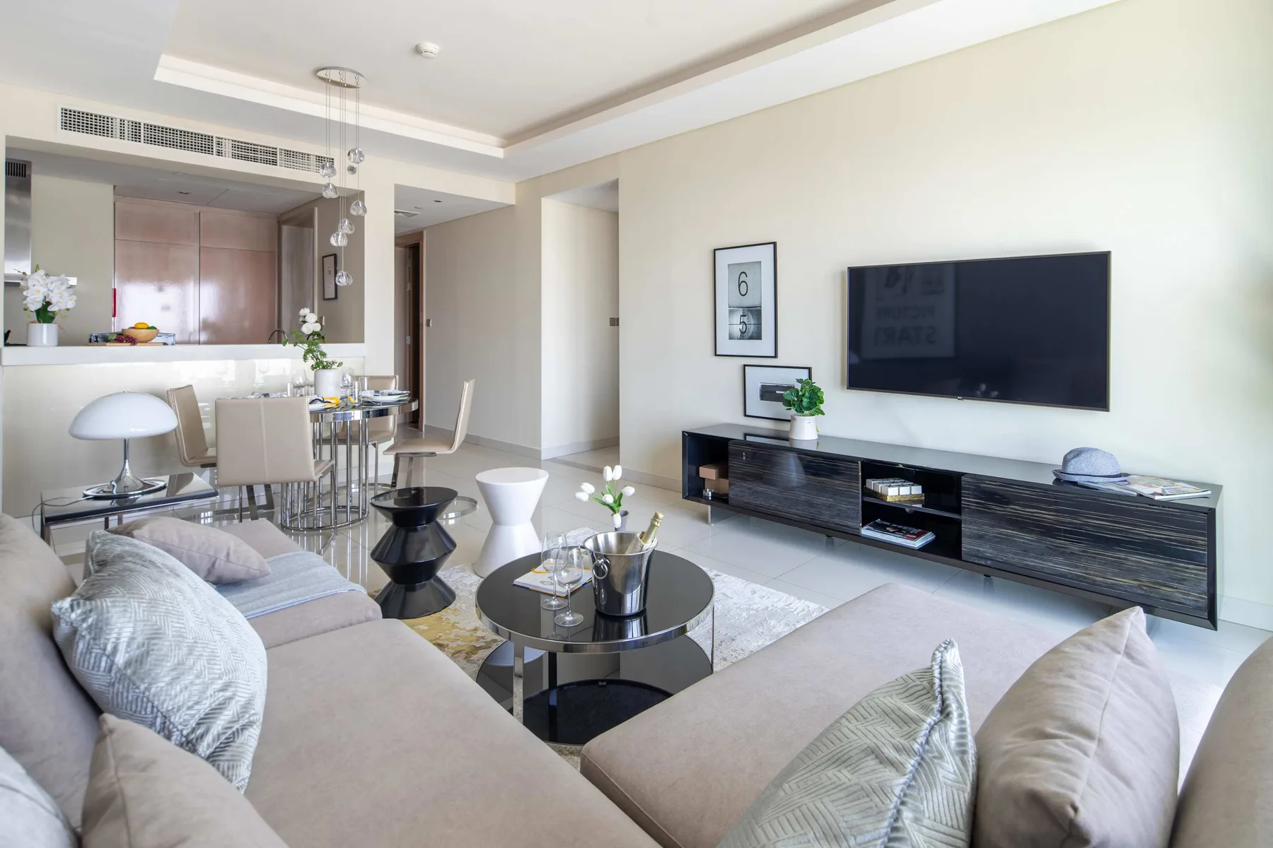 Una sala luminosa con asientos, un televisor y un comedor abierto.