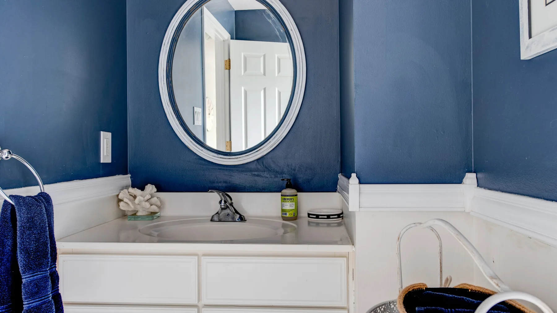 A bathroom vanity with a sink, oval mirror, and blue walls.