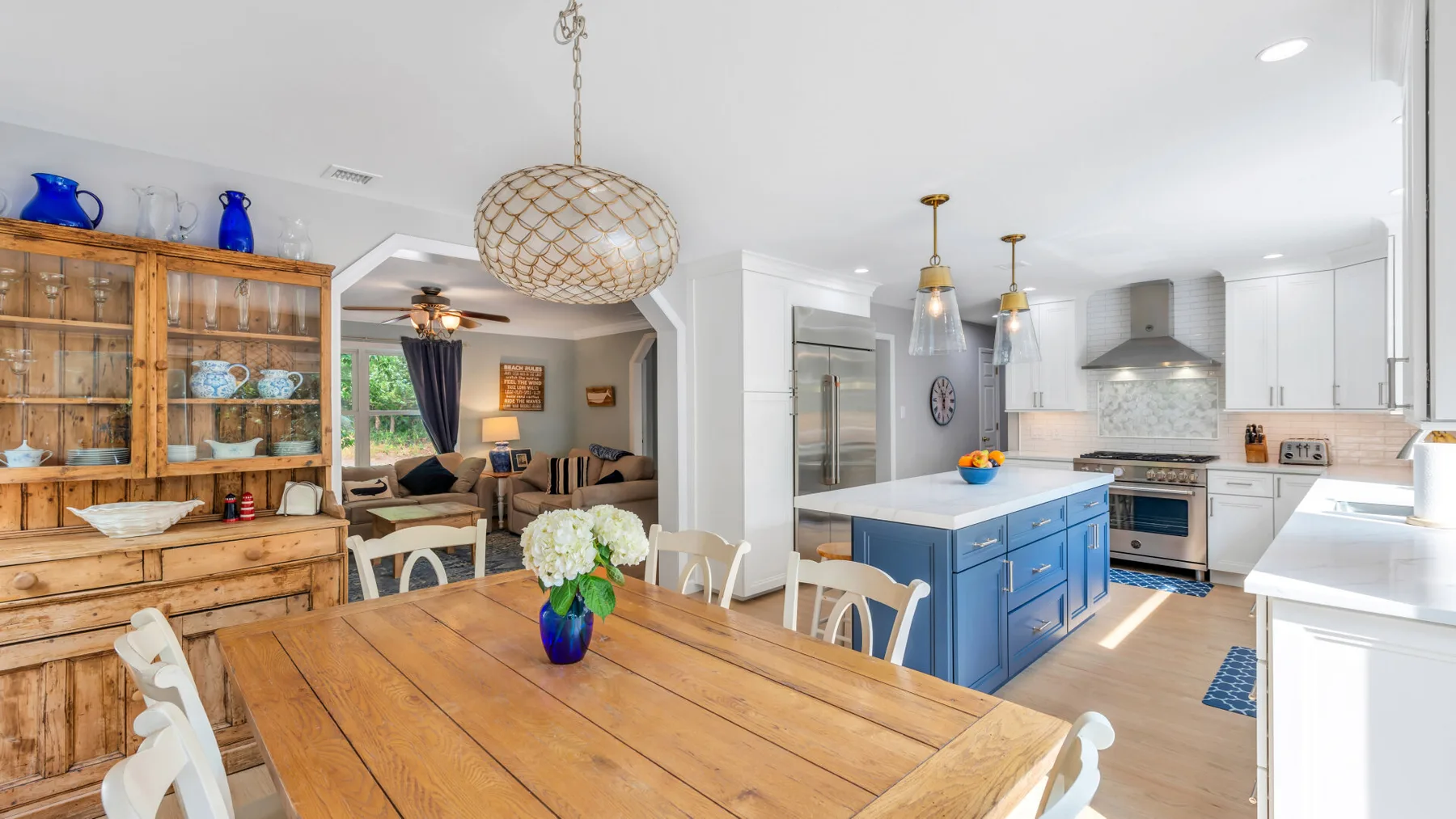 An open dining and kitchen area with a wooden table and blue island.