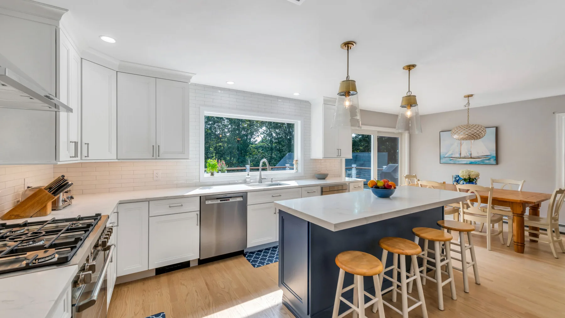 A bright kitchen with white cabinets, a central island, and an adjoining dining area.