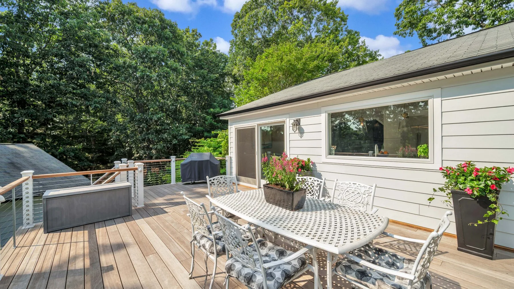 A backyard deck with outdoor dining furniture and potted flowers.