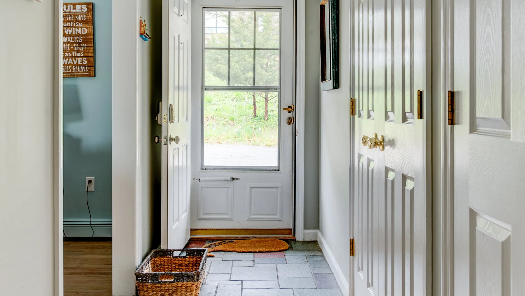 A bright entryway with a tiled floor, built-in cabinets, and a glazed exterior door.