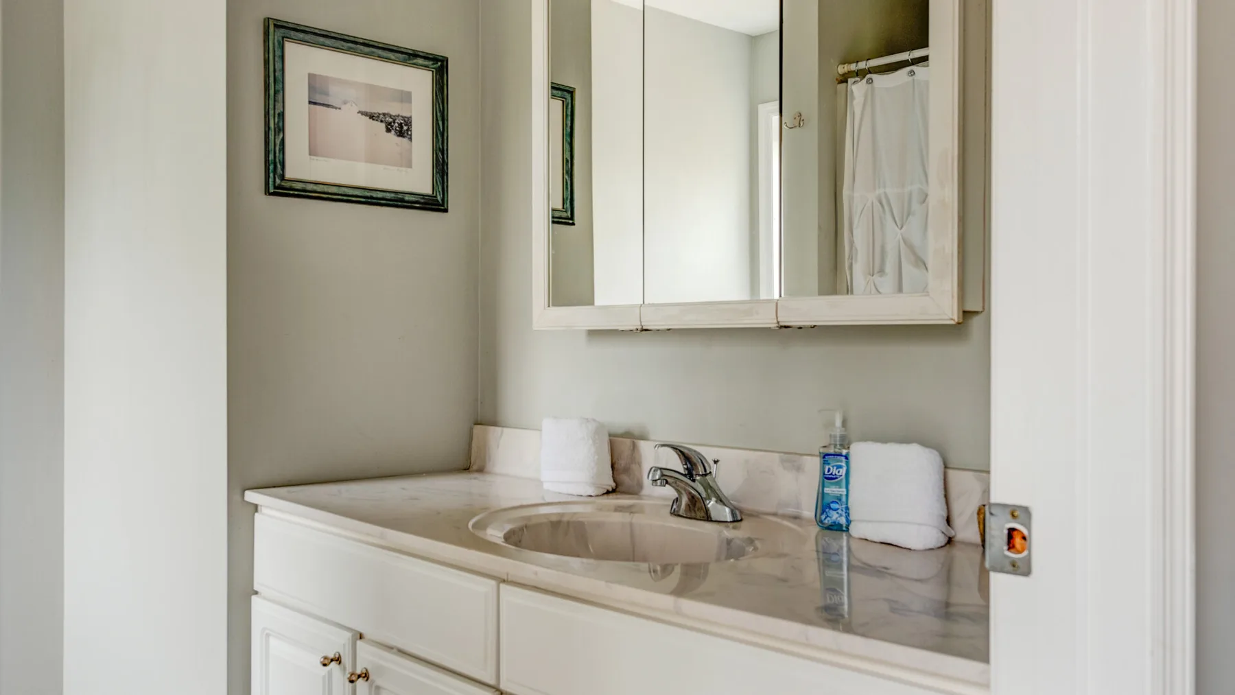 A bathroom vanity with a sink, mirror, and framed wall art.
