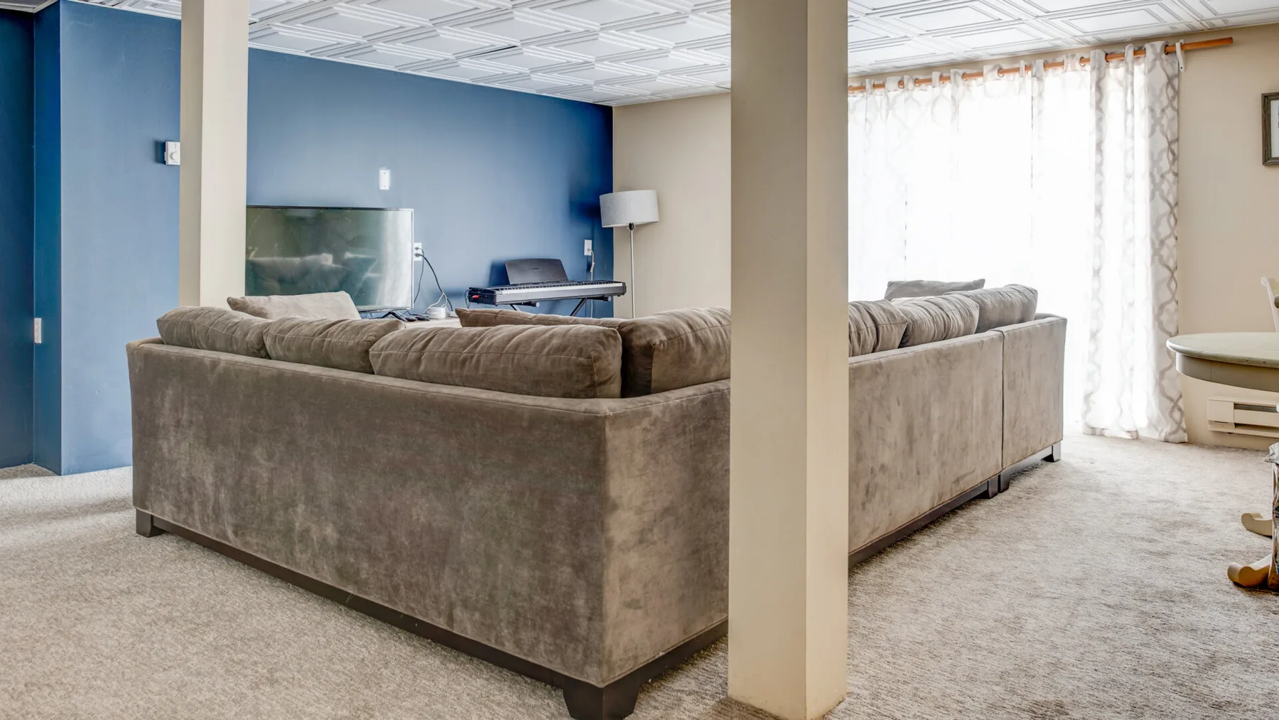 A living room with a large sectional seating area and a blue accent wall.