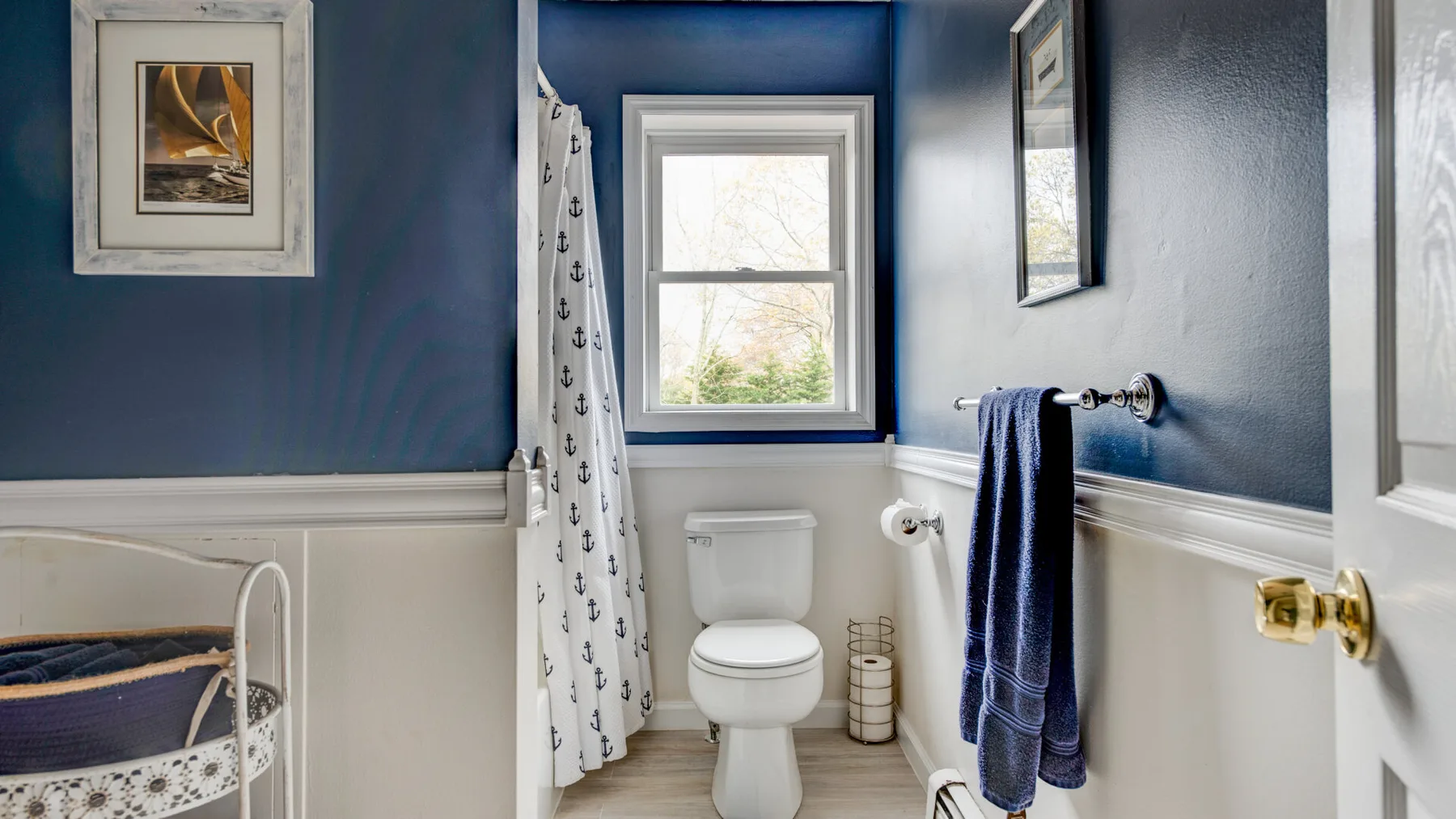 A bathroom with a toilet, window, and patterned shower curtain.