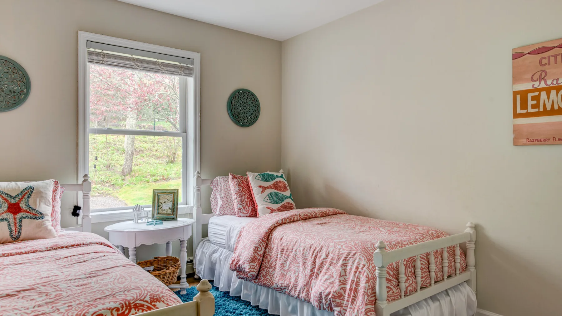 A bedroom with two beds dressed in patterned bedding beside a window.