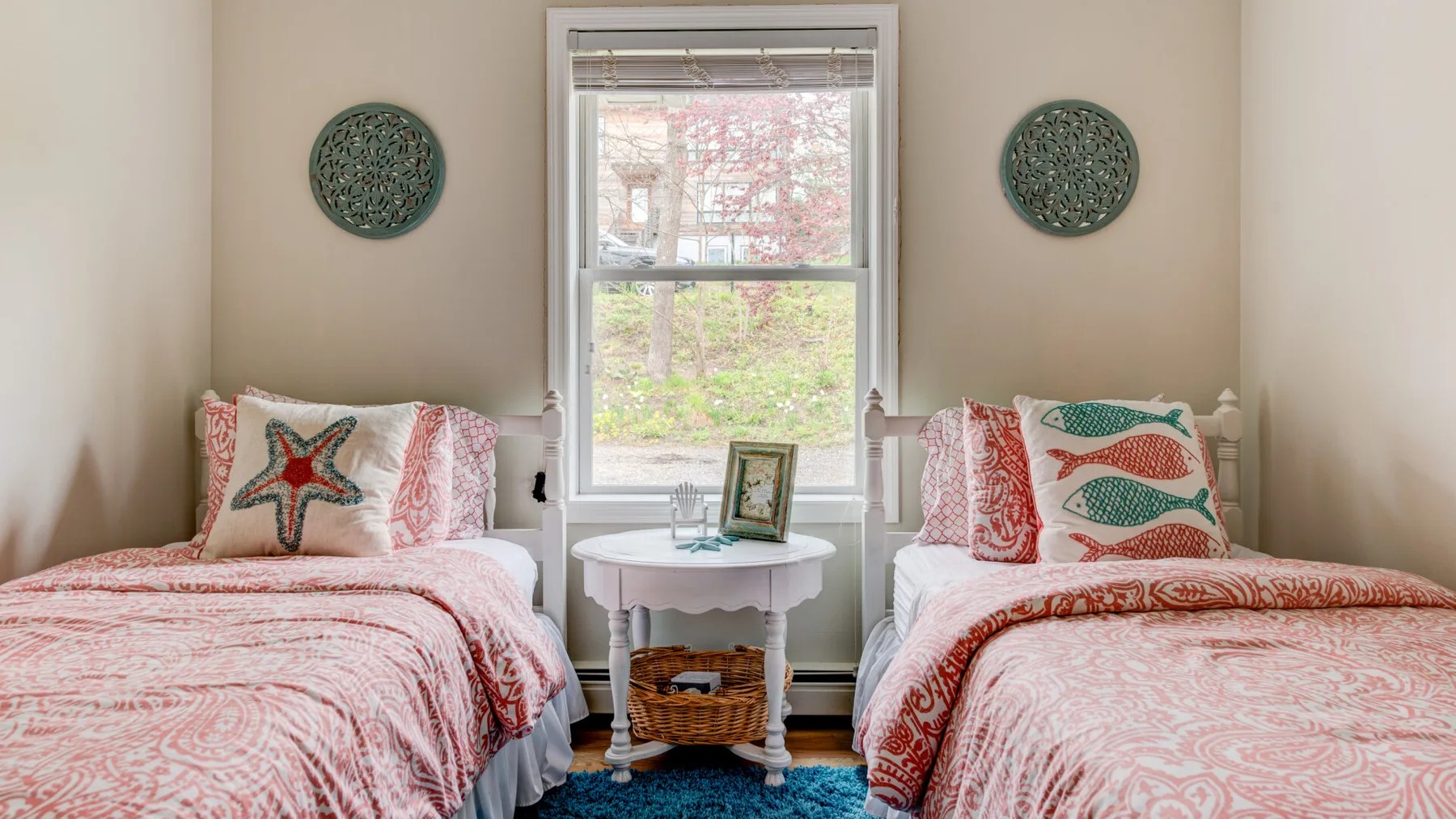 A twin bedroom with two beds flanking a central window.
