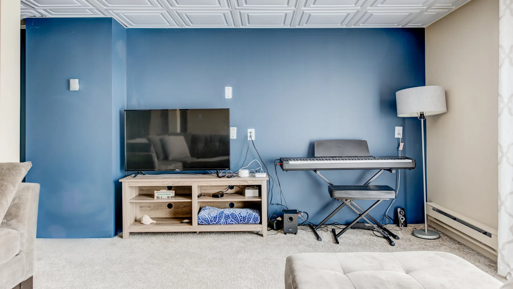 A living room with a television, keyboard, and floor lamp.