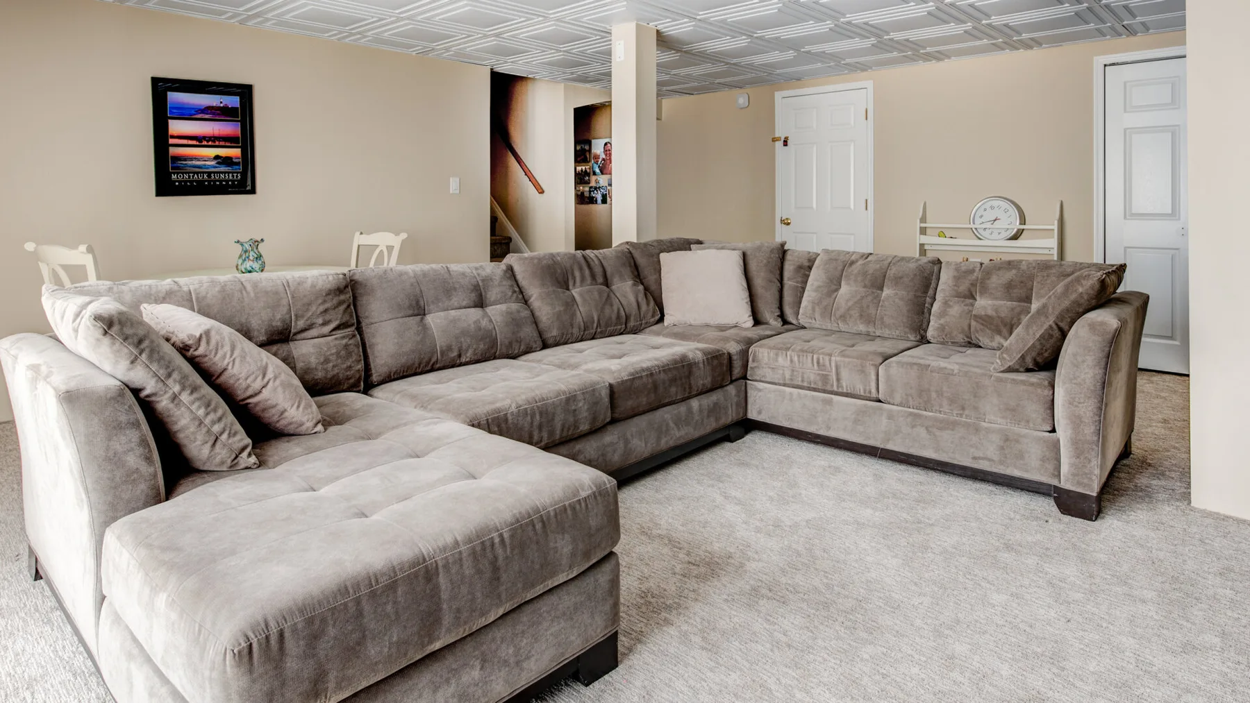 A basement living room with a large sectional seating area and wall-mounted television.