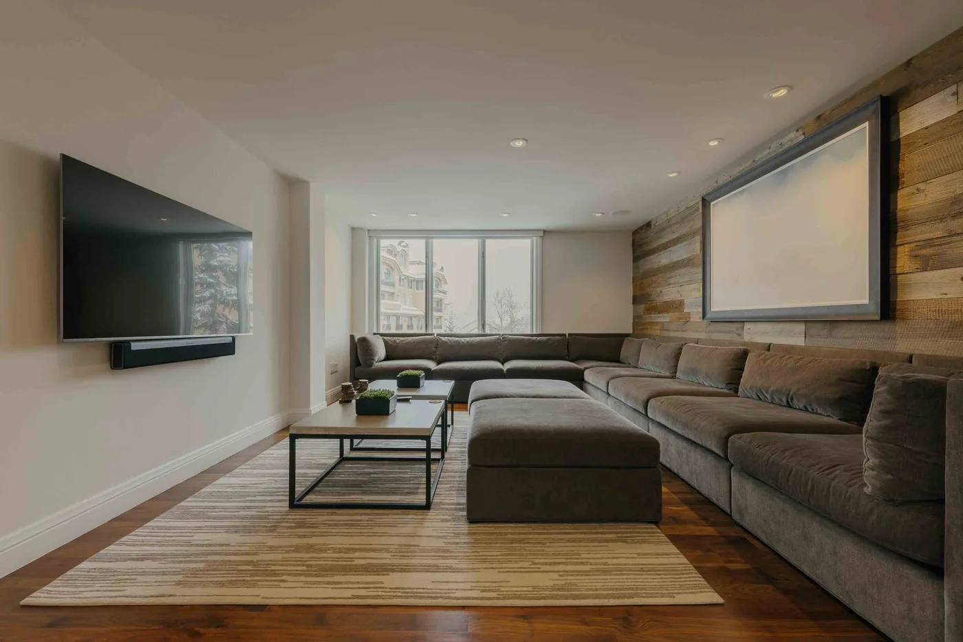 A living room with sectional seating, a coffee table, and large windows.