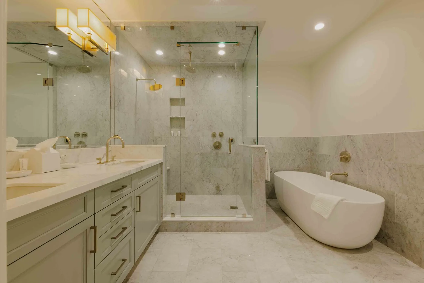 A bright bathroom with a glass shower, long vanity, and freestanding bathtub.
