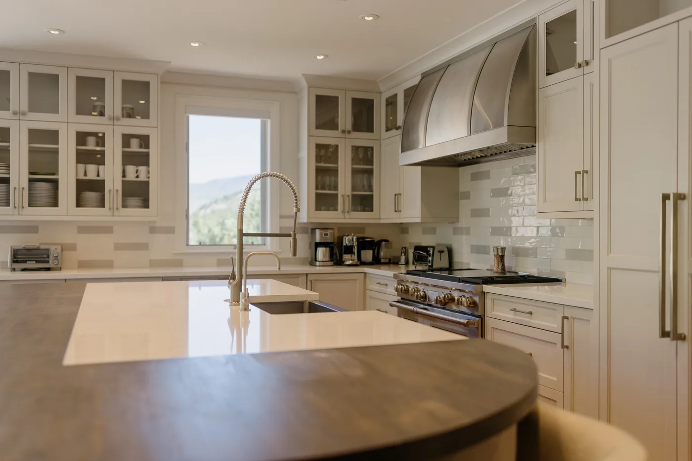 A bright kitchen with pale cabinetry, a central island, and a cooking range.